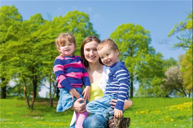 Alleinerziehende mit zwei Kindern auf grüner Wiese